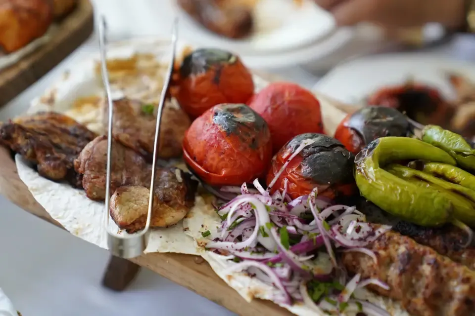 A plate of mixed kebab served with charred tomatoes and onions on flat bread