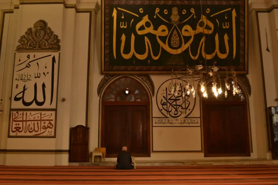 Intricate black and gold Islamic calligraphy painted on the stone pillars inside the mosque