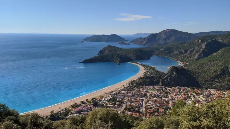 A panoramic view of the Fethiye coastline with yachts anchored in a serene bay under a clear blue sky