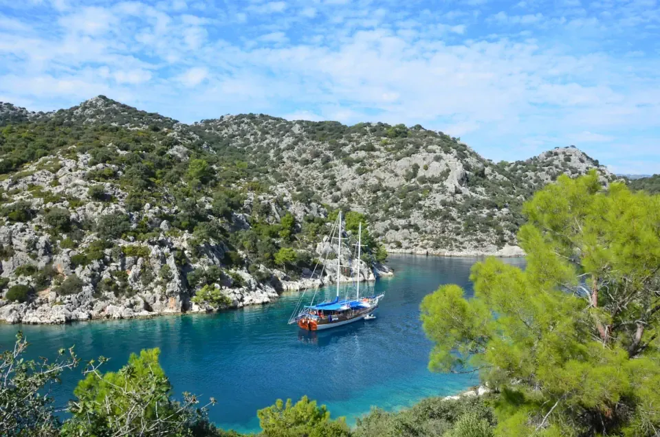 A luxury wooden gulet by the rugged green cliffs along the Turkish Riviera