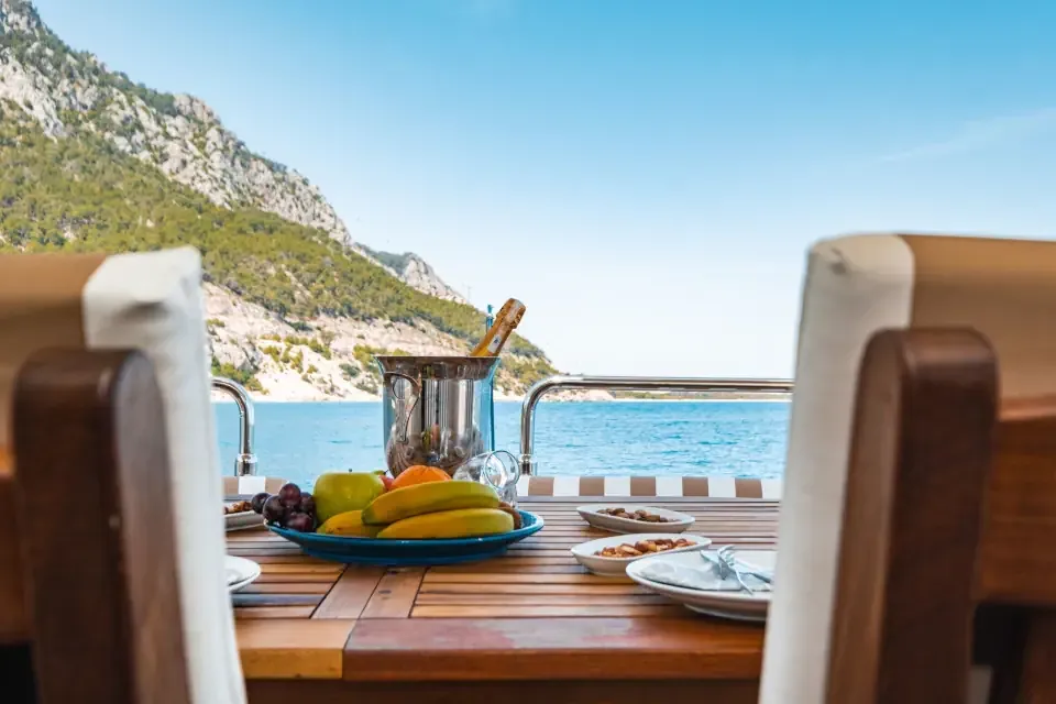 A dining table set up on the wooden deck of a gulet yacht