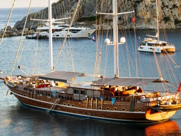 A wooden Turkish gulet yacht anchored in a secluded turquoise cove