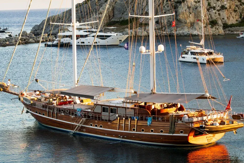 A wooden Turkish gulet yacht anchored in a secluded turquoise cove