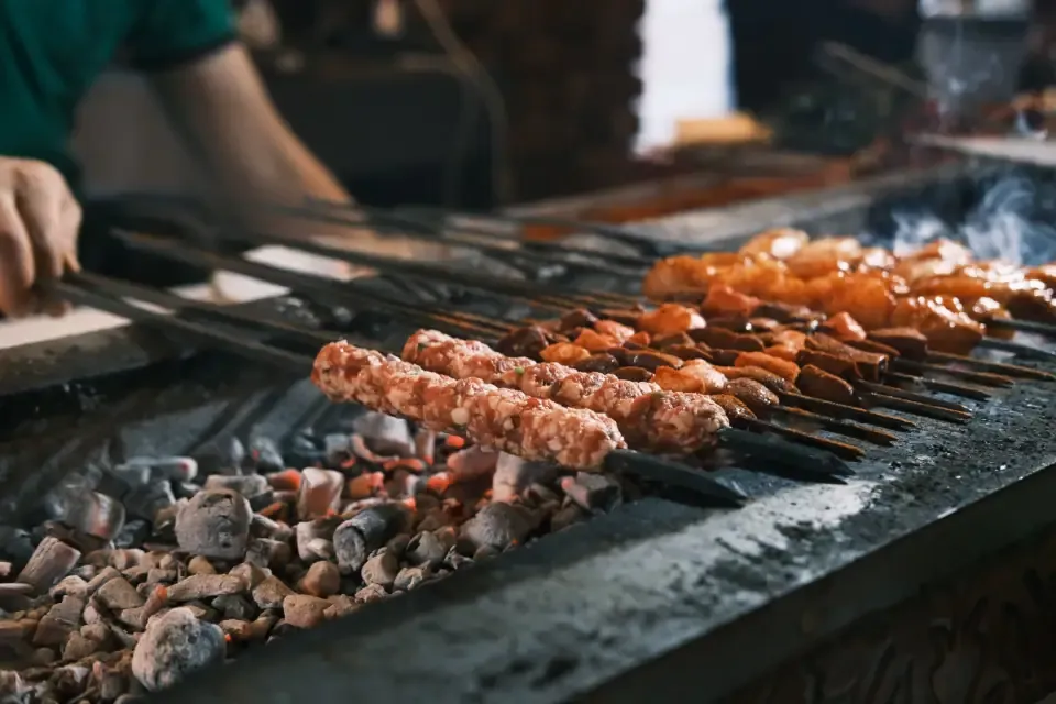 Open charcoal grill lined with skewered kebabs inside a historic Kazancilar restaurant