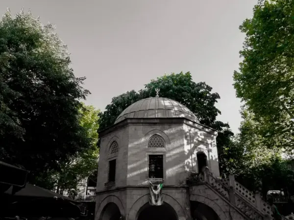 Historic two story stone courtyard of Koza Han in Bursa with tea tables under shade trees