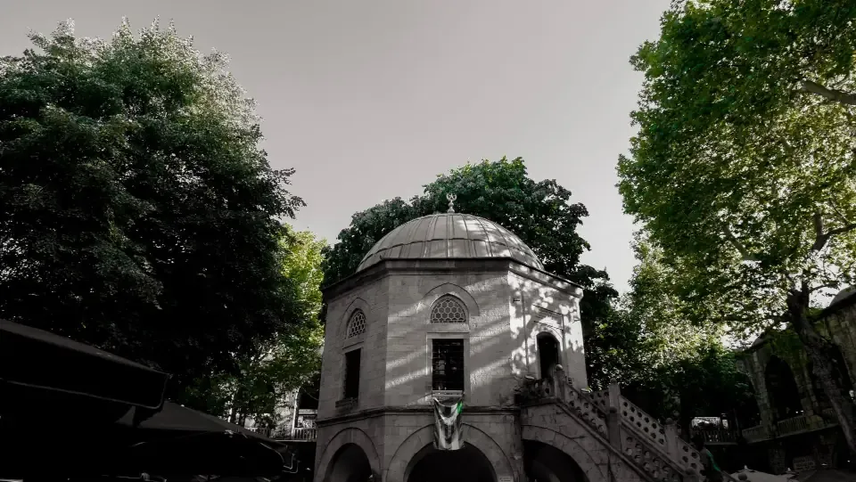 Historic two story stone courtyard of Koza Han in Bursa with tea tables under shade trees