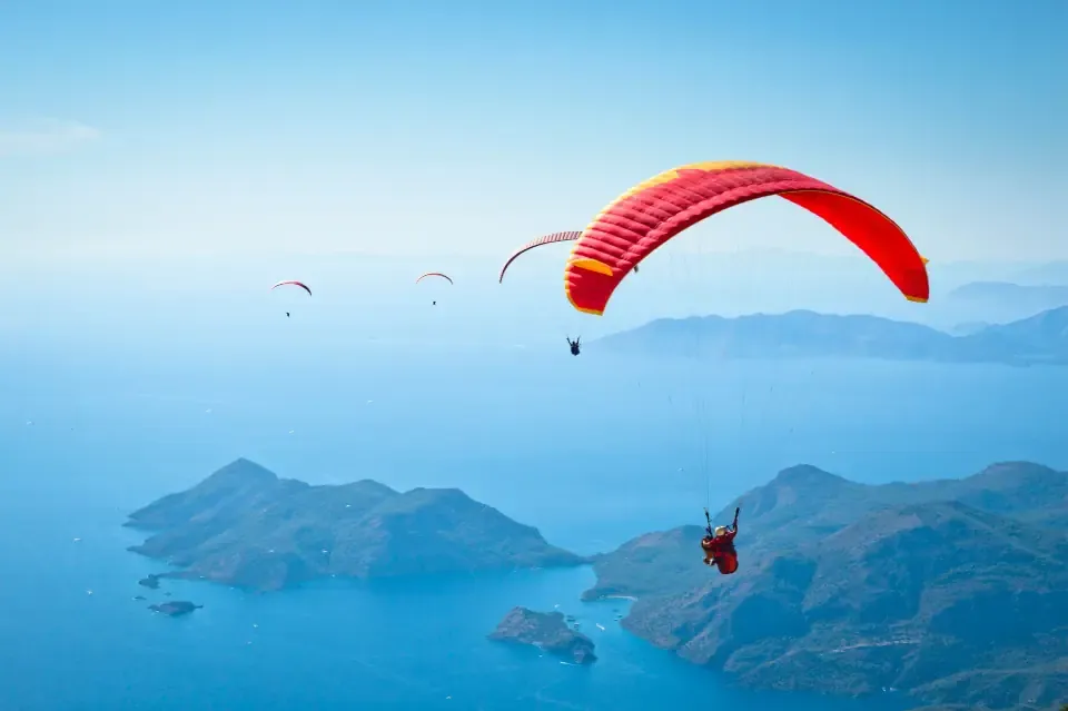 A tandem paraglider soaring high above the vibrant turquoise waters of the Blue Lagoon in Oludeniz