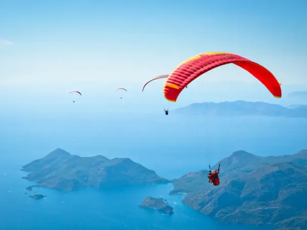A tandem paraglider soaring high above the vibrant turquoise waters of the Blue Lagoon in Oludeniz