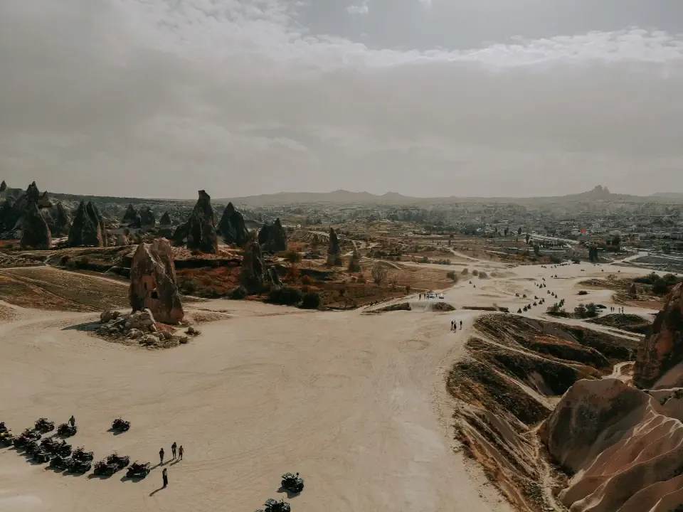 A group of travelers riding ATV quad bikes through the dusty trails of Red Valley in Cappadocia